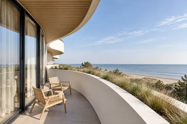 Balkon z pełną białą balustradą, trawy w donicy, dwa krzesła i horyzont morza